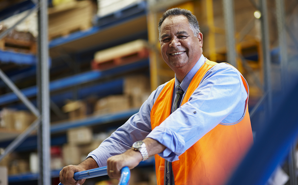 A man in a warehouse pushing a trolley