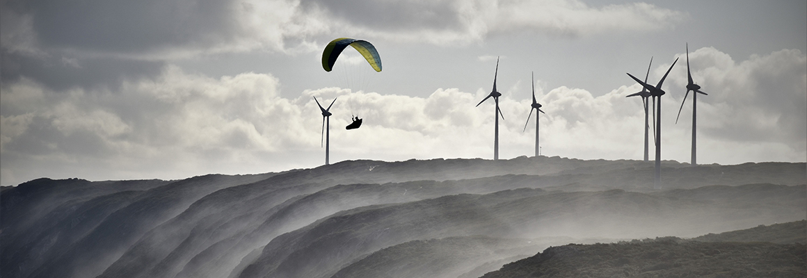 A person parasailing near a wind farm