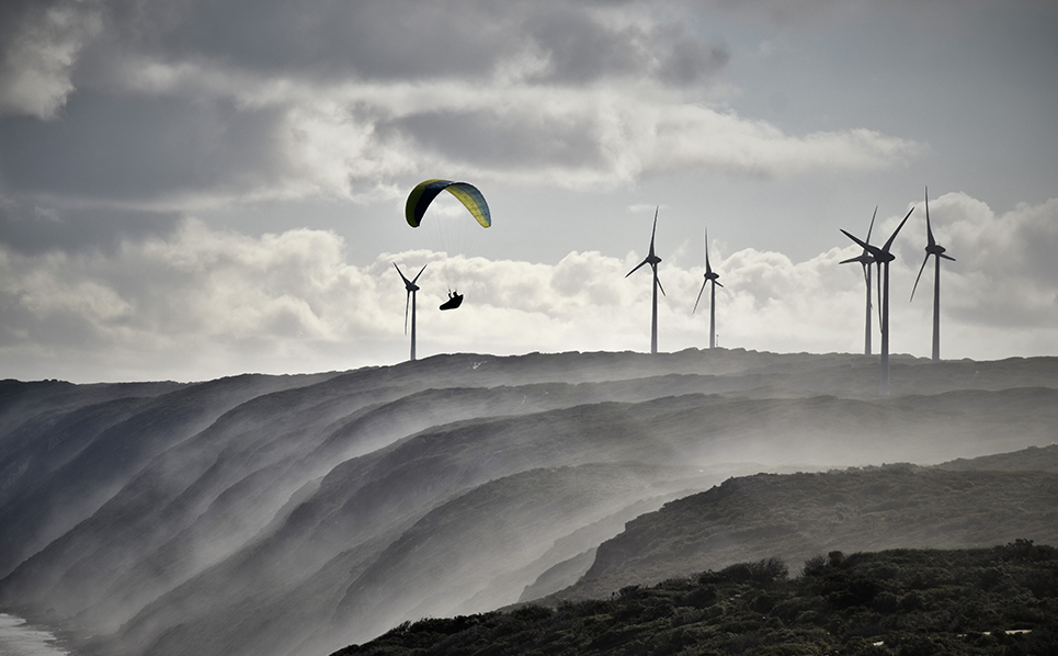 A person parasailing near a wind farm