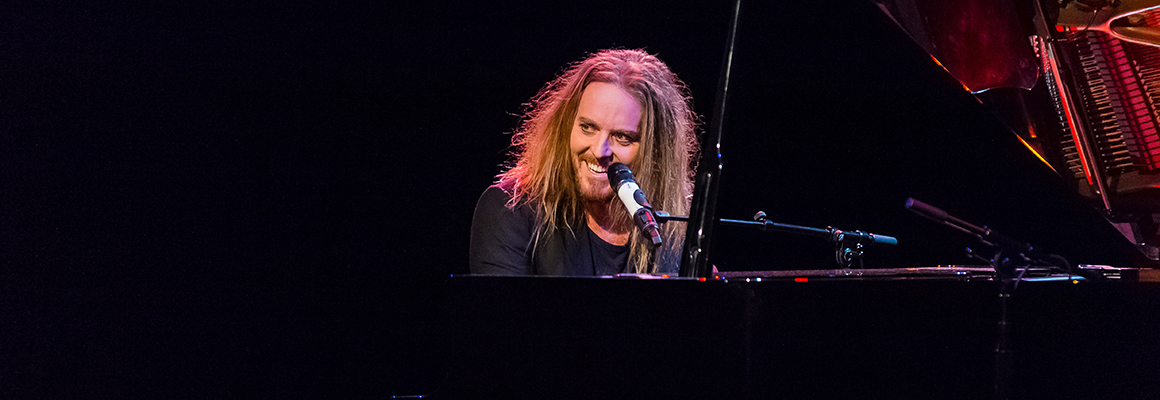 Tim Minchin at a piano