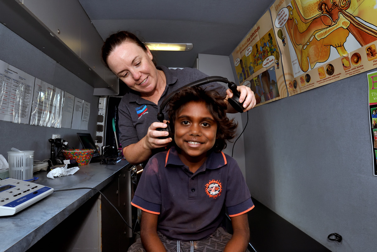 A girl receives an ear health screening from a Chevron Pilbara Ear Health Program staff member