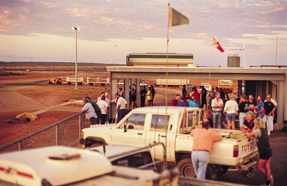 Workers standing around trucks near the airport on Barrow Island